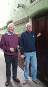 Len (right) fixing the bolts and new peephole cover with help from Gordon.